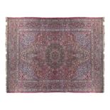 A ANTIQUE TABRIZ WOOL CAPRET, the red ground decorated with all over floral motifs in blue,