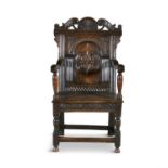 A LATE 17TH CENTURY OAK WAINSCOT ARMCHAIR, the shaped rectangular back with scroll carved cresting,