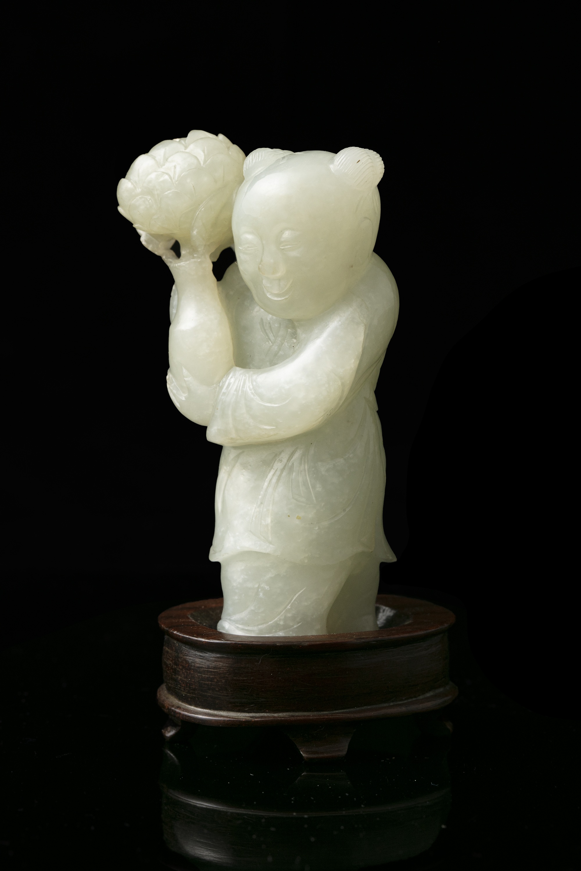 A WHITE JADE FIGURE OF A STANDING BOY WITH A LOTUS FLOWER VASE China, Qing Dynasty, 19th century