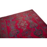 A TURKISH WOOL CARPET, in the traditional taste, the iron red ground decorated with floral motifs