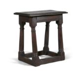 AN 17TH CENTURY OAK JOINT STOOL, with moulded panel seat, on four splayed column supports,