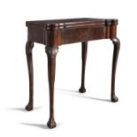 A GEORGE III MAHOGANY CARD TABLE, the folding top set with round candle stands and counterwells and