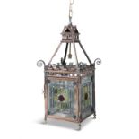AN EDWARDIAN BRASS AND STAINED GLASS FOUR PANEL HALL LANTERN, of square shape hung on four chains,
