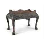 AN IRISH MAHOGANY DECANTER STAND, MID 18TH CENTURY, the bold frieze in deep relief centred by