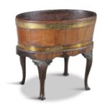 A GEORGE III MAHOGANY BRASS BOUND OVAL WINE COOLER ON STAND, with shell carved cabriole legs and