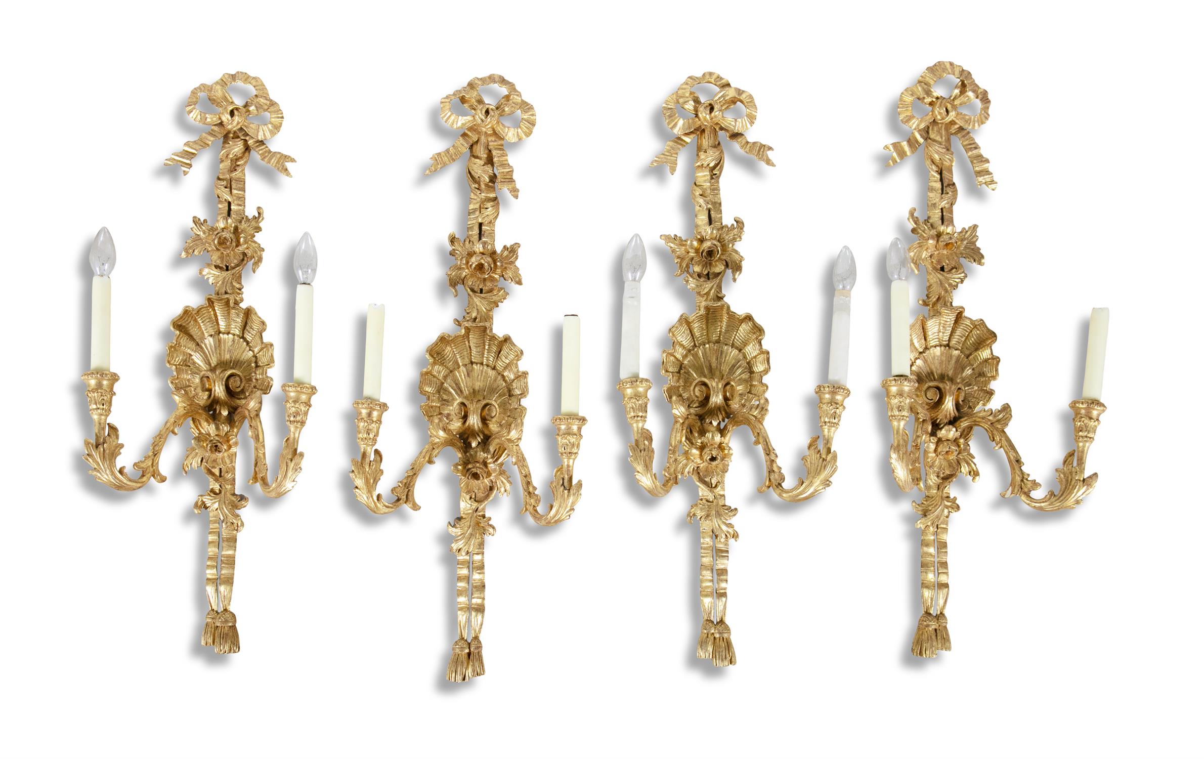 A SET OF FOUR GEORGIAN STYLE GILTWOOD TWO-LIGHT WALL SCONCES, surmounted with tied ribbons bedecked