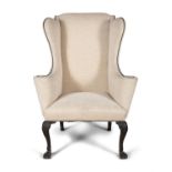 AN IRISH GEORGE II MAHOGANY FRAMED WINGBACK ARMCHAIR, covered in a soft cream upholstery and