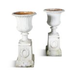 A PAIR OF WHITE PAINTED CAST IRON GARDEN URNS OF CAMPAGNA FORM, with beaded rim and fluted body on