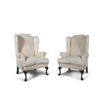 A PAIR OF GEORGIAN REVIVAL CREAM UPHOLSTERED WINGBACK ARMCHAIRS, covered in a floral damask,