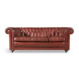 A CHESTERFIELD BUTTON BACK THREE-SEATER SETTEE, upholstered in burnt orange leather,