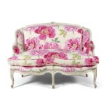 A VICTORIAN LADIES SETTEE, the cream painted frame carved with floral and foliate decoration,