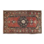 A PERSIAN RED GROUND WOOL CARPET, early 20th century, of rectangular shape, woven with large