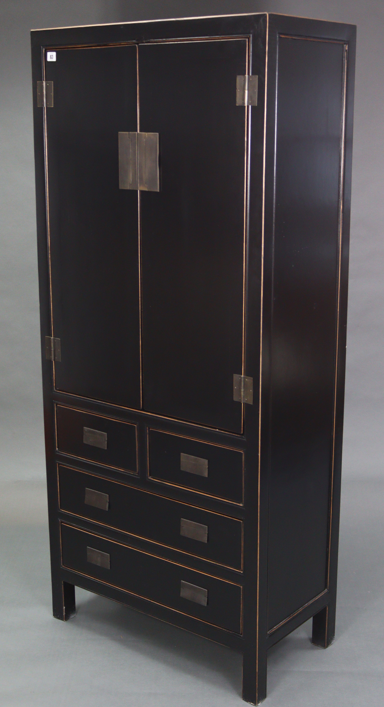 A Chinese style black & gold lacquered wardrobe, enclosed by pair of panel doors above two short &