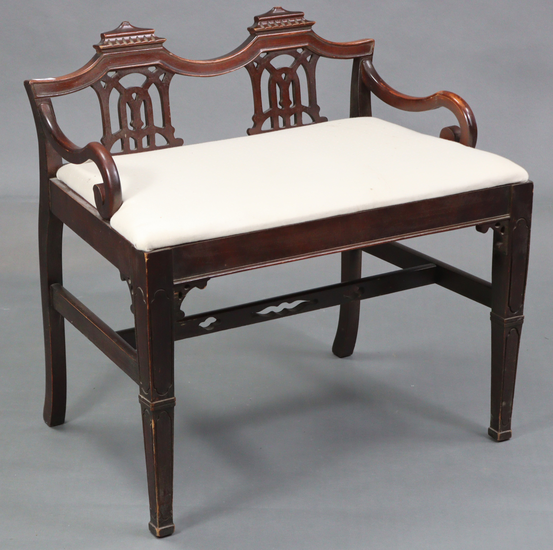 A 19th century style mahogany stool with pierced splats to the back, with open scroll arms, padded