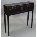 A Chinese style black & gold lacquered side table, with cupboard to centre enclosed by pair of panel