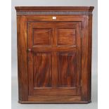 A 19th century mahogany hanging corner cupboard, fitted two shelves enclosed by a fielded panel