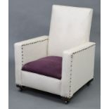 A mid-20th century square-back child’s easy chair upholstered cream rexine, & on castors.