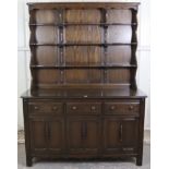An Ercol dark elm dresser, the upper part fitted open shelves & with panelled back, the base