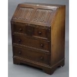 A reproduction oak bureau, with fitted interior enclosed by linen-fold panel fall-front, above three