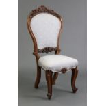 A Victorian walnut balloon-back nursing chair, with padded foliate-carved back & seat, on cabriole