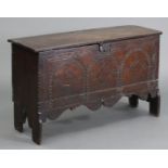 A 17th century joined oak small coffer of six-plank construction, the carved three-panel front