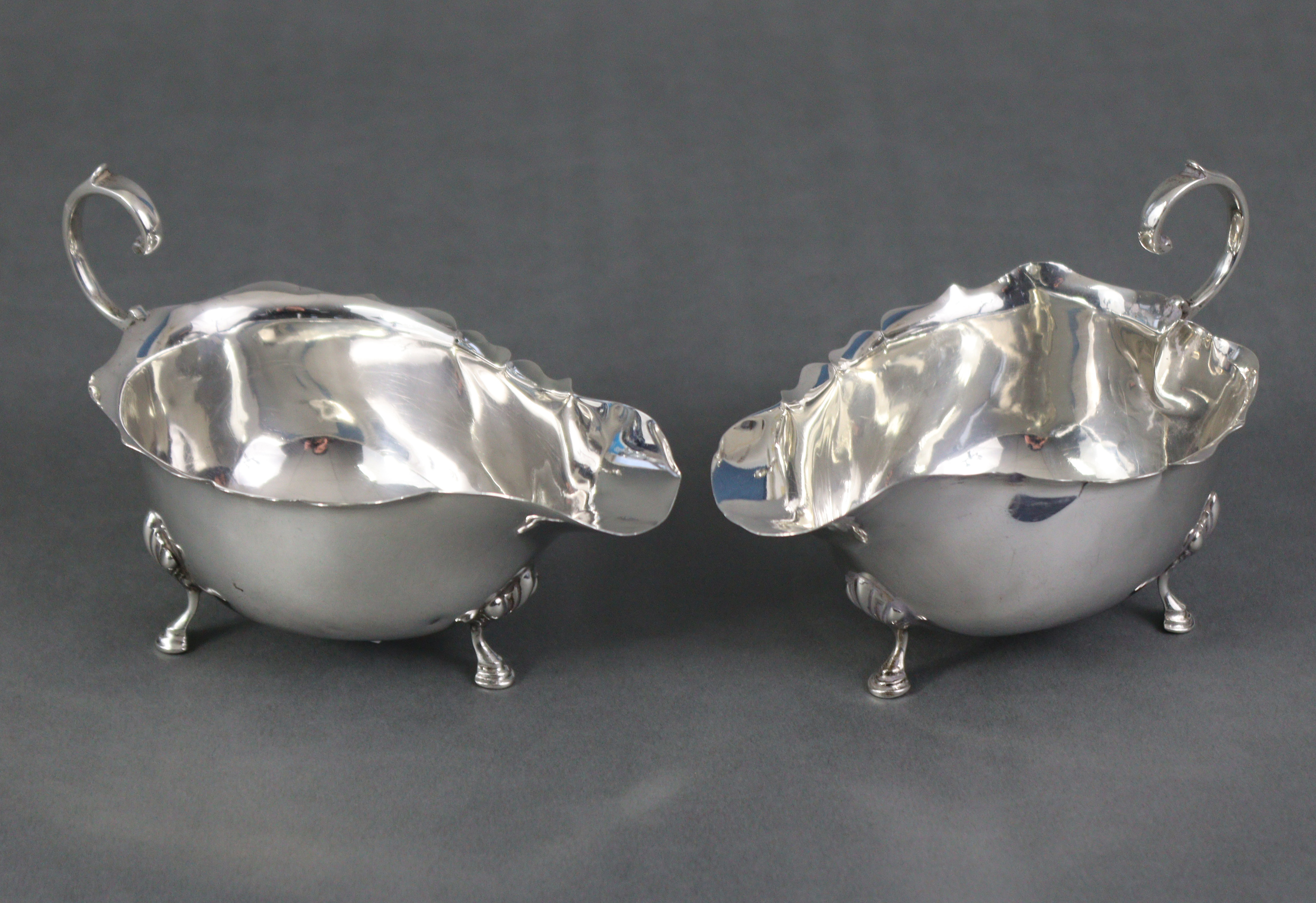 A pair of Georgian-style silver sauce boats, each with scroll handle & card-cut rims, on three shell - Image 4 of 5