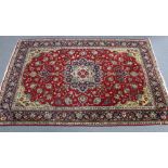 A large Persian rug of crimson ground, with central cartouche, floral spandrels, in ivory & blue