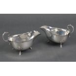 A pair of Georgian-style silver sauce boats, each with scroll handle & card-cut rims, on three shell