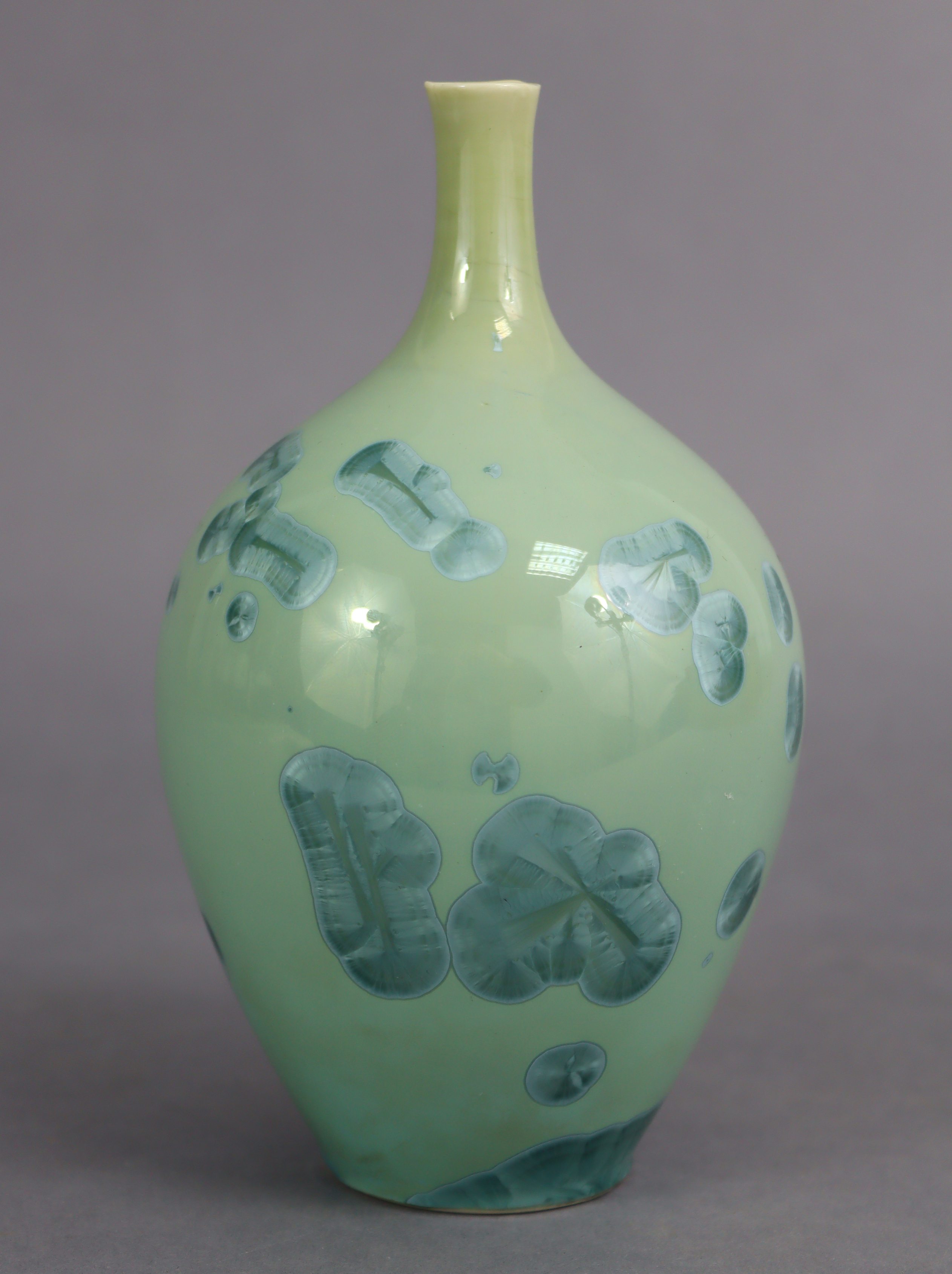 A contemporary studio porcelain bottle vase with narrow neck, celadon glazed with turquoise