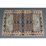 A chain stitch wool rug of ivory ground with a multicoloured repeating geometric design with in a