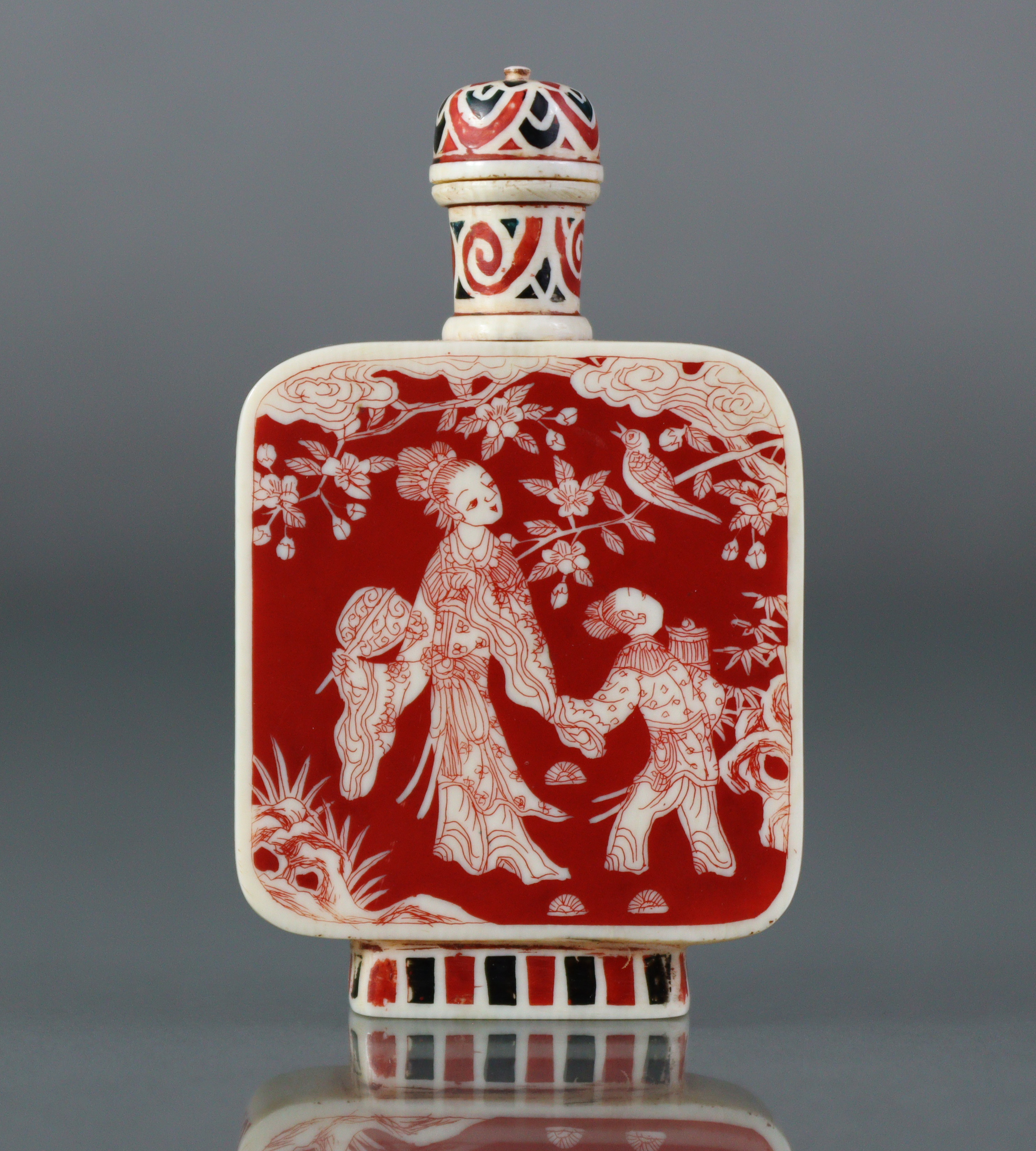 A Chinese stained ivory snuff bottle of flat-sided rectangular form, each side decorated with