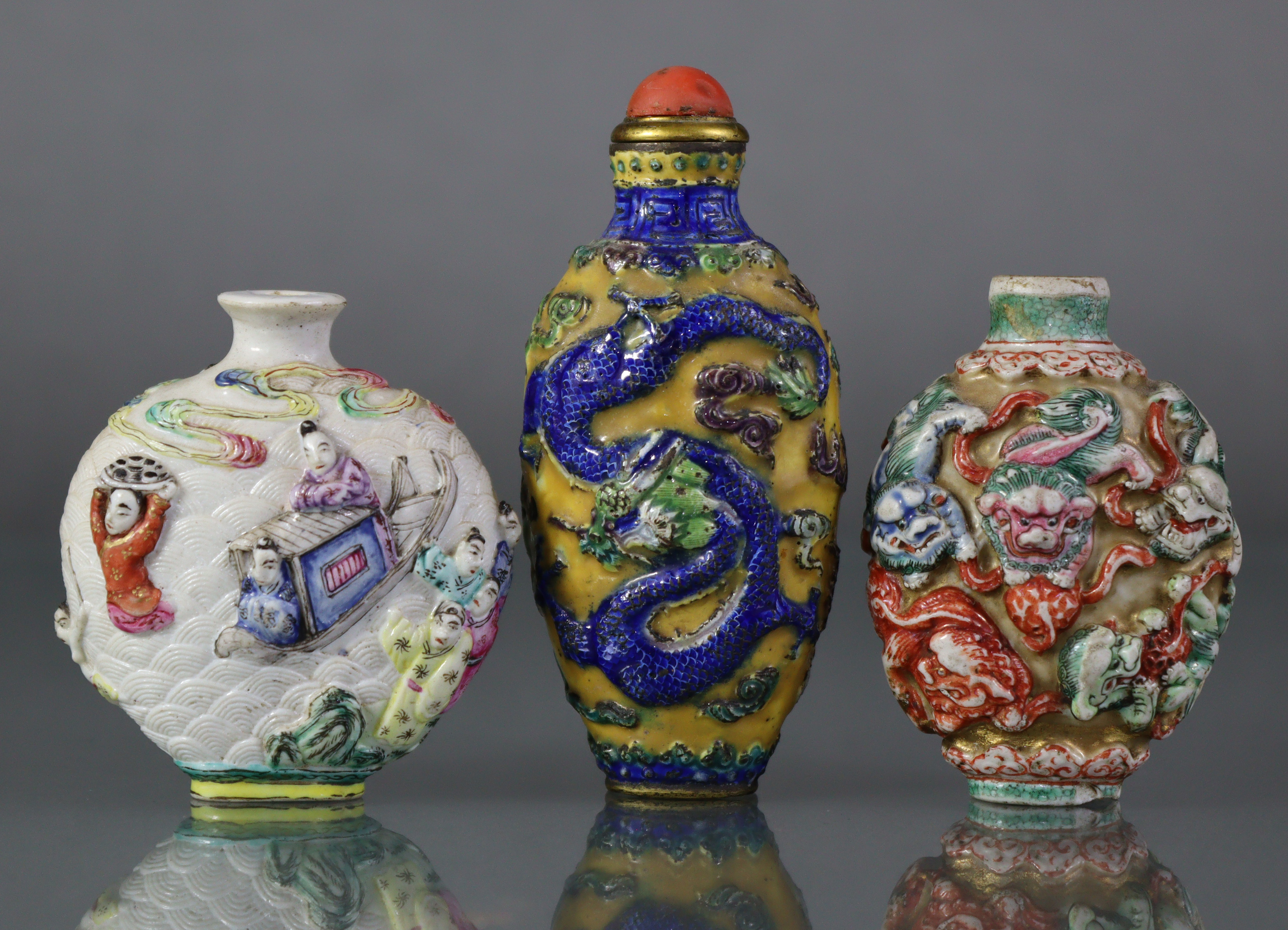 Three Chinese moulded porcelain snuff bottles, the largest decorated with a dragon & phoenix in