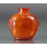 A Chinese carved golden amber snuff bottle of compressed form, with mask-&-ring handles to each