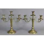 A pair of three-branch brass table candelabra with scroll supports, each on round pedestal foot, 13”