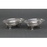 A pair of Edwardian silver oval sweetmeat dishes with pierced sides, each on four shaped feet,