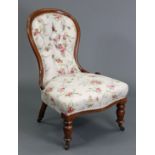A Victorian walnut spoon-back nursing chair, upholstered buttoned floral material, on turned legs