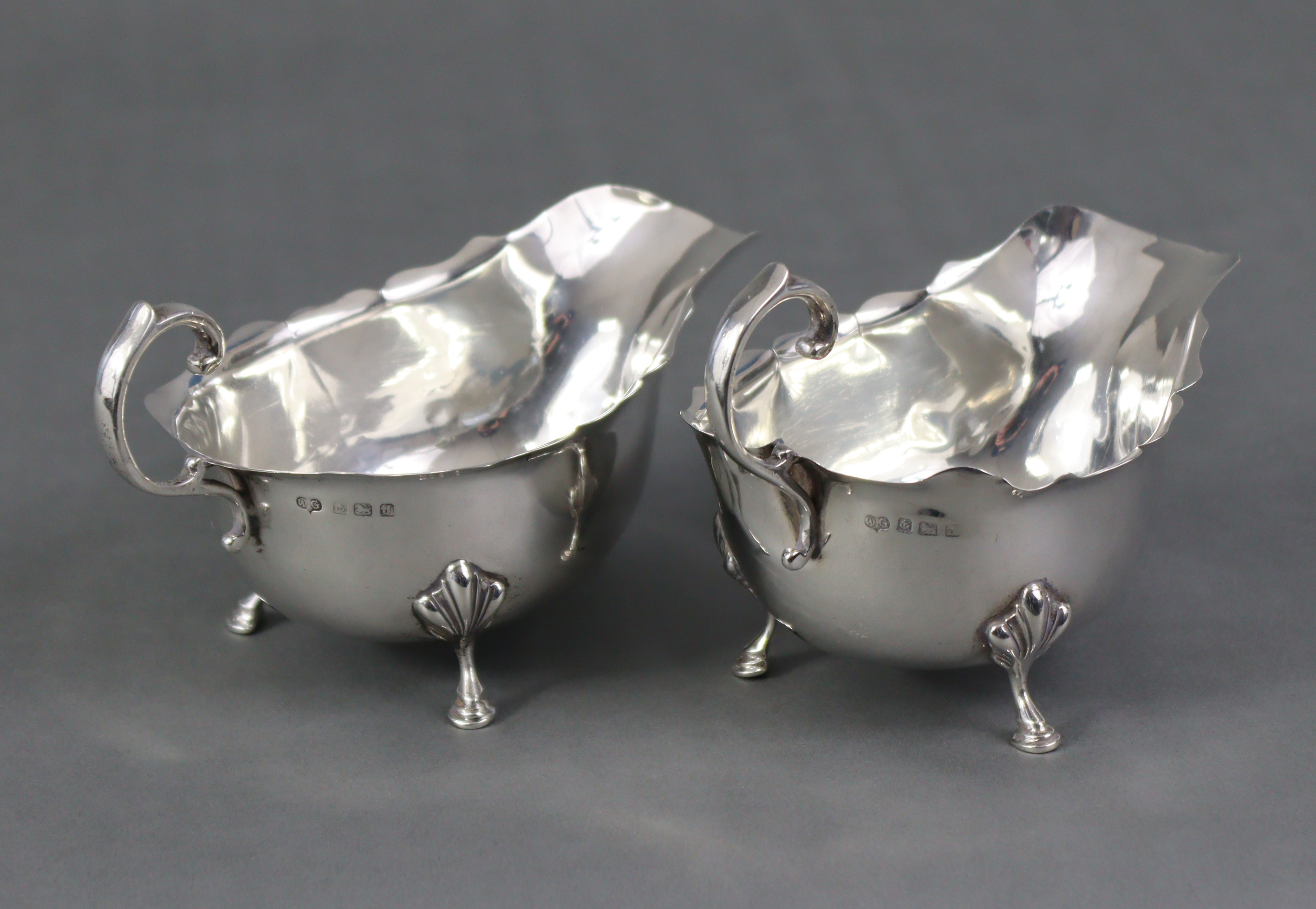 A pair of Georgian-style silver sauce boats, each with scroll handle & card-cut rims, on three shell - Image 2 of 5