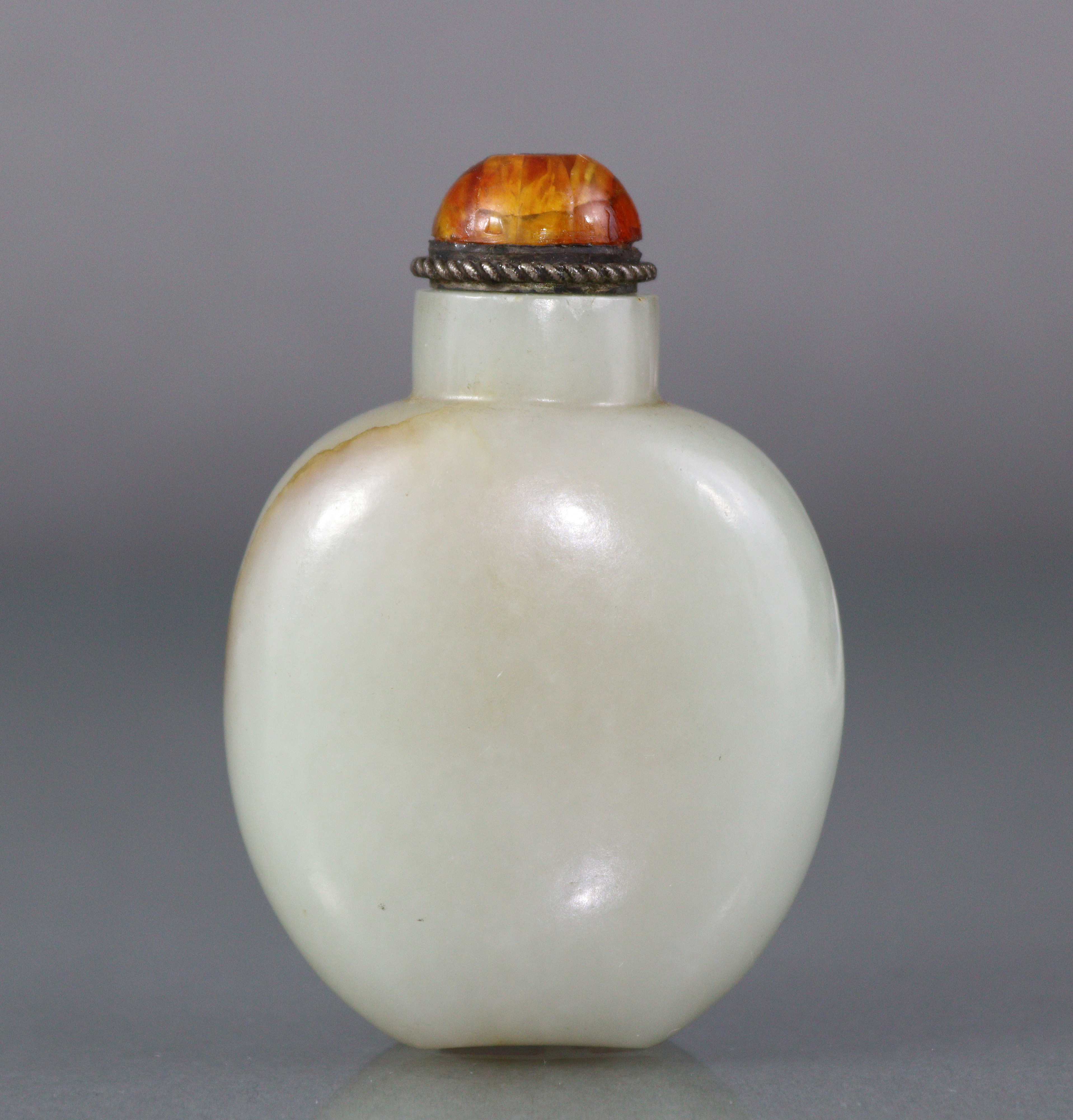 A Chinese pale celadon jade snuff bottle of rounded ovoid form, with russet coloured vein to one