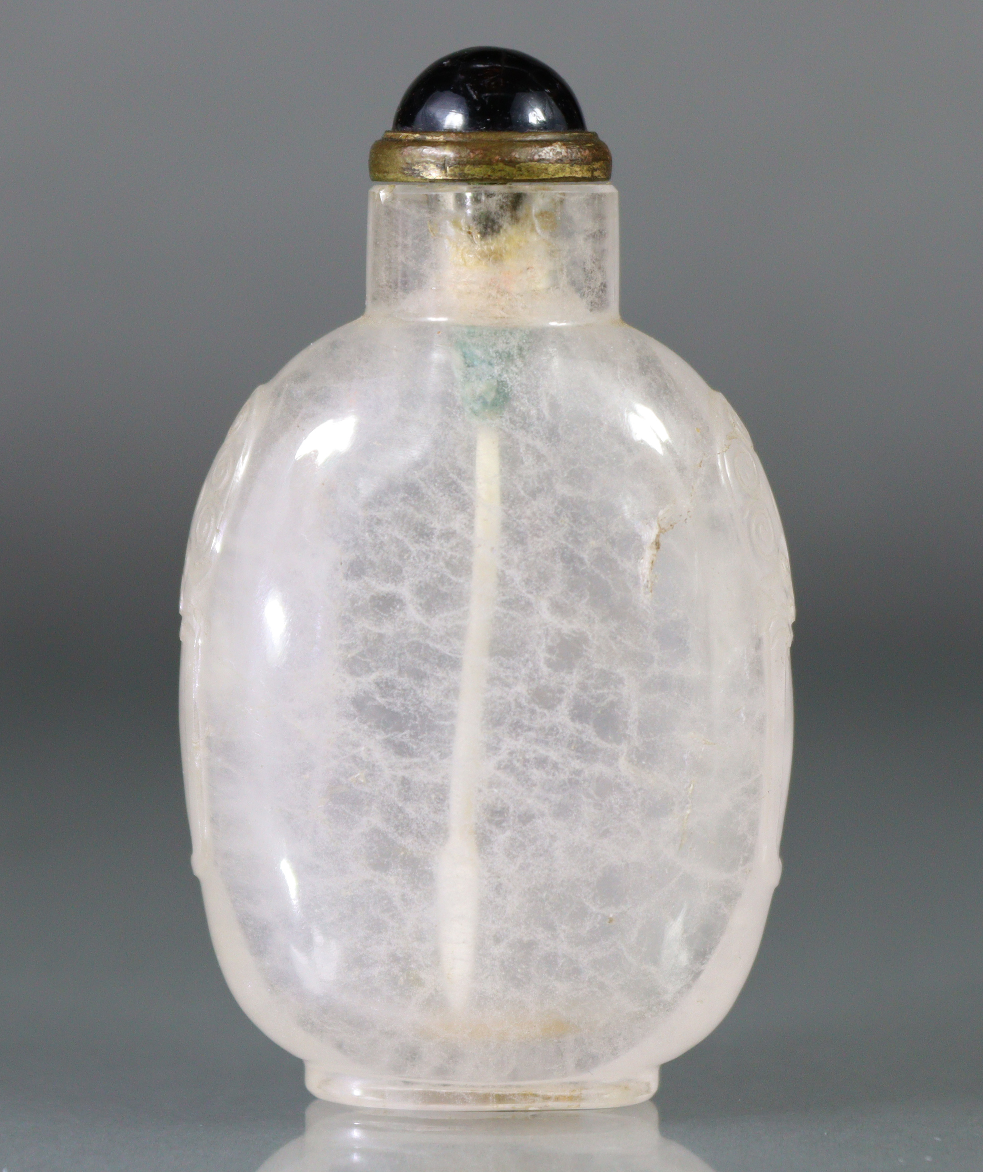 A Chinese carved crystal snuff bottle of rounded ovoid form, with mask-&-ring handles to each
