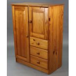 A pine nursery cupboard fitted four shelves to the left-hand side enclosed by fielded panel door,