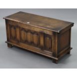 A reproduction oak blanket box with hinged lift-lid, linen-fold panel front, & on block feet, 37½”