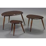 An Ercol-style dark elm nest of three occasional tables each on three round tapered legs.