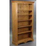 A pine tall standing open bookcase with six adjustable shelves, & on shaped plinth base, 43” wide