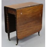 A late Victorian mahogany drop-leaf dining table on four ring-turned tapered legs with brass