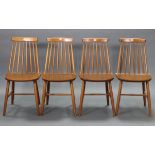A set of four spindle-back kitchen chairs with hard seats, & on round tapered legs with spindle