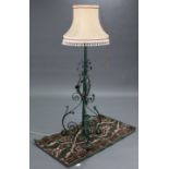 A green painted wrought-iron telescopic standard lamp on three shaped supports, with shade; & a