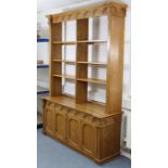 A light oak tall side unit the upper part with carved frieze & with six adjustable open shelves, the