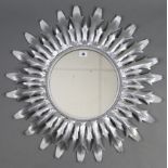 A circular wall mirror in silvered-metal sunburst frame, 25½” diameter.
