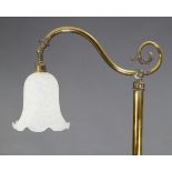 A Victorian brass standard lamp on triform base, and with single scroll-arm, with shade, 66¾” high.