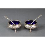 A pair of circular silver salt cellars of compressed round form, each on three pad feet, London 1860
